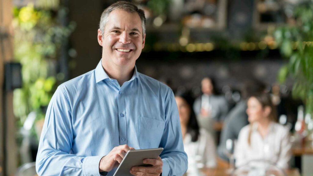 Owner looking at his tablet to Attract More Visitors to Your Google Business Profile