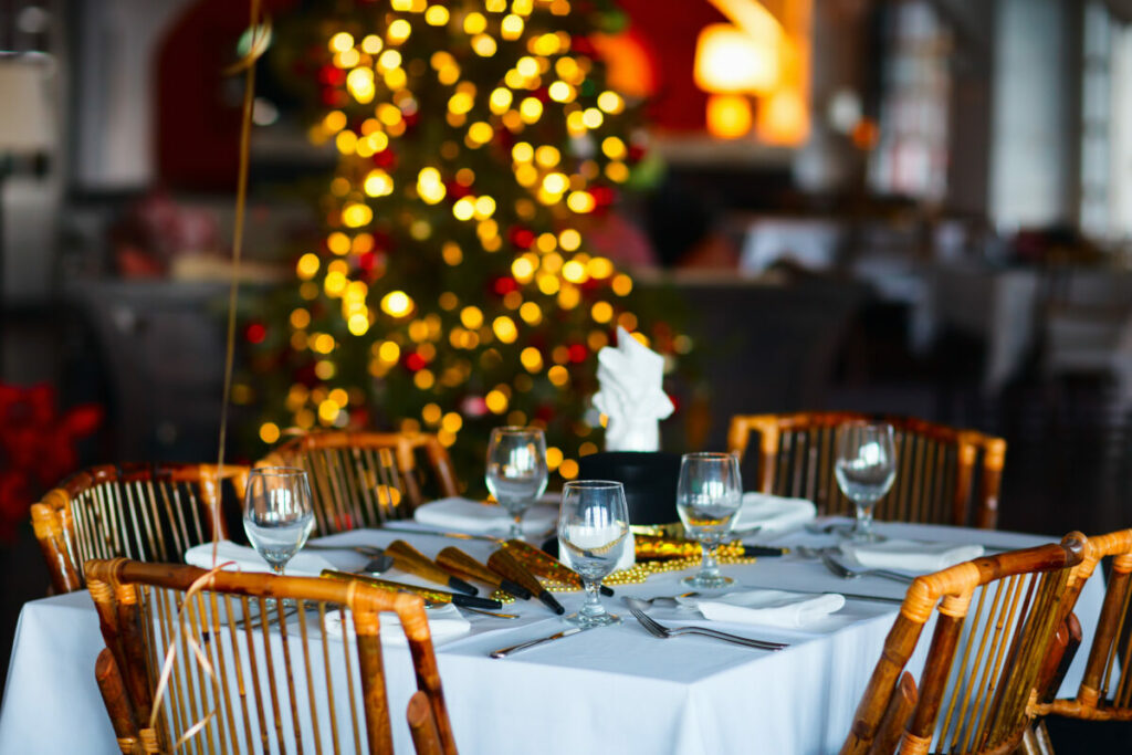 Holiday-themed restaurant table setting with Christmas tree lights glowing in the background