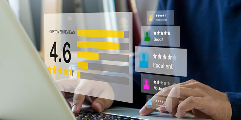 Person typing on a laptop with floating graphics showing customer review ratings and feedback.