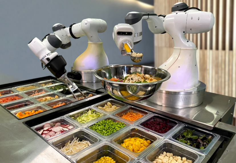 Robotic arms preparing a fresh salad using various ingredients at an automated restaurant station.