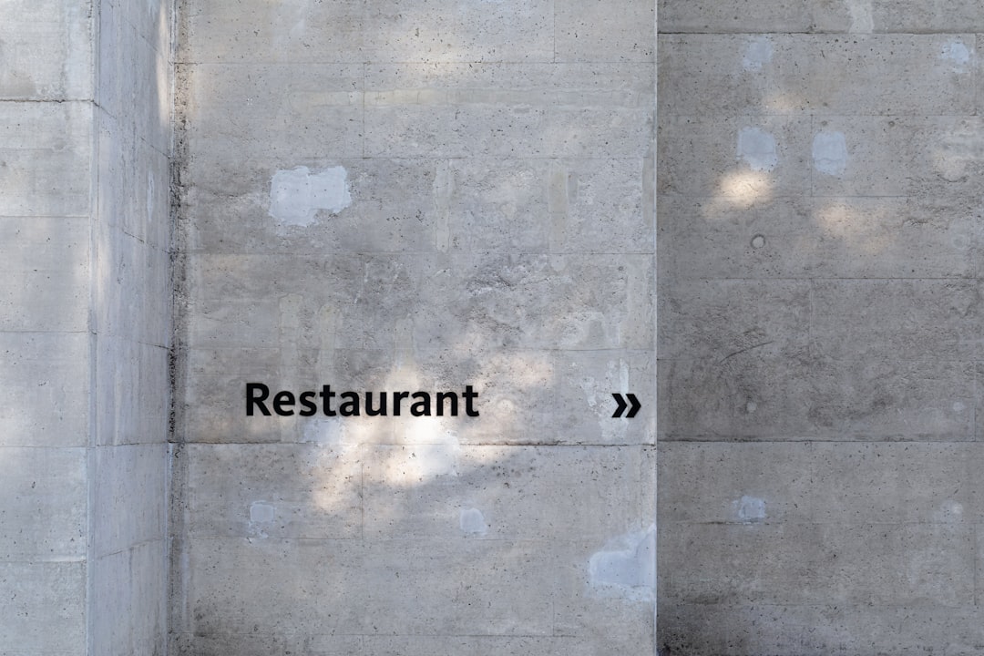 Minimalist concrete wall with the word "Restaurant" and directional arrows pointing right.