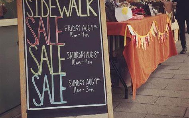 Sidewalk sale chalkboard sign outside a local store